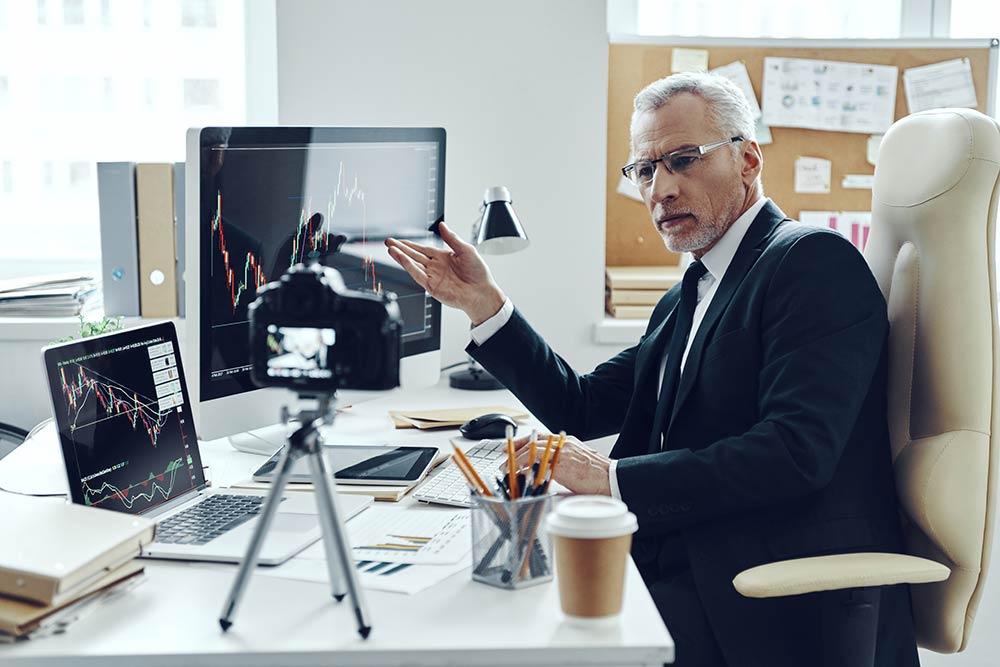 Man at desktop lokking into a camera which is recording him